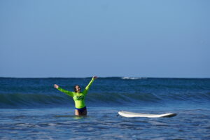 Surfer girl shows joy after she completes her wave while surfing on her surf and fitness vacation at her Samara Surf Camp