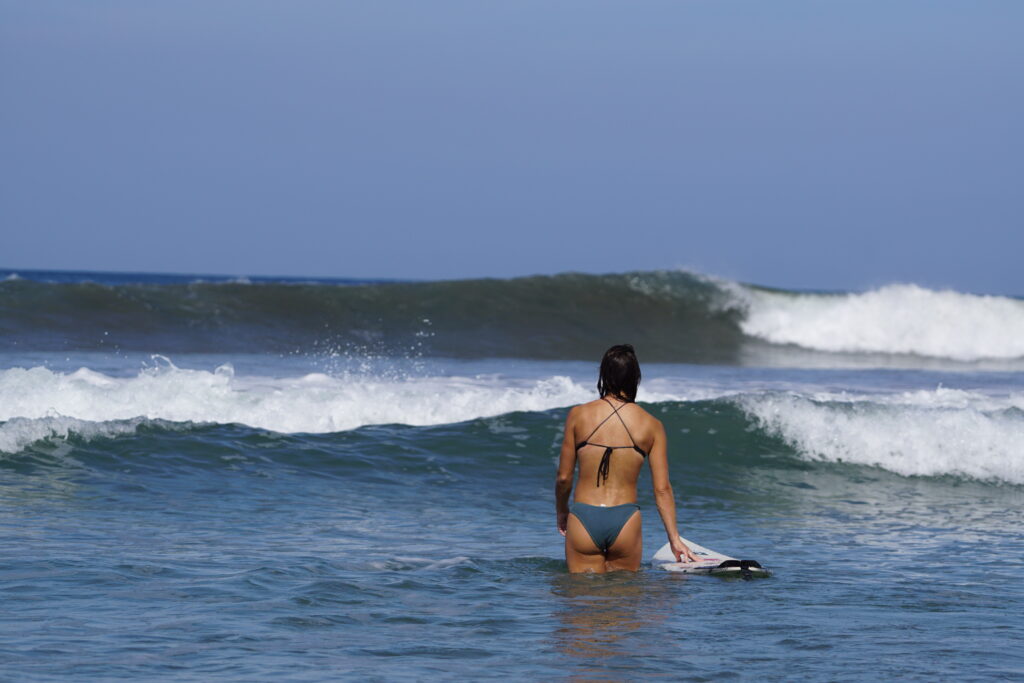 Girl walks toward a breaking wave in Guiones, Costa Rica