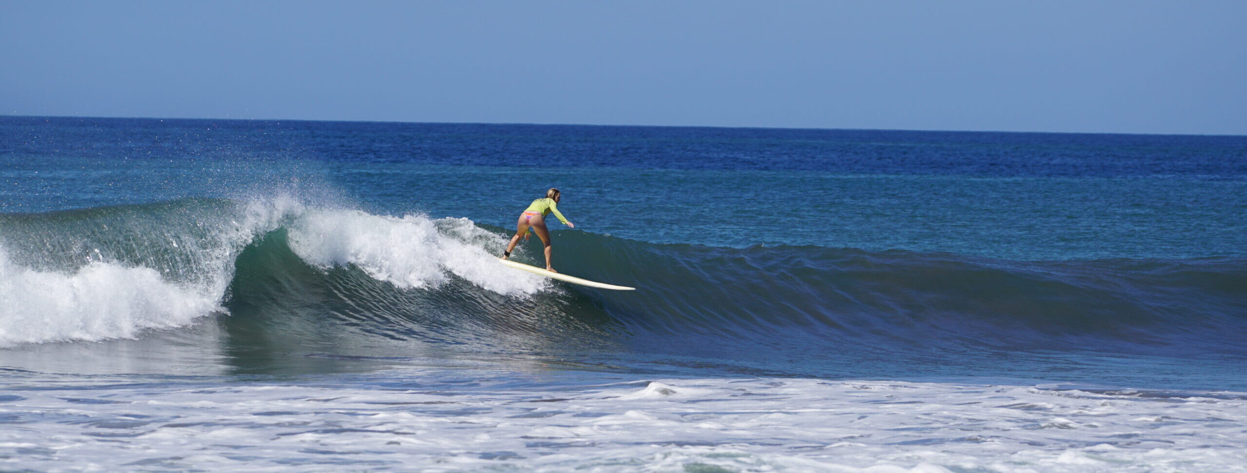 Surfer girl with surf coaching goes down the line in Costa Rica